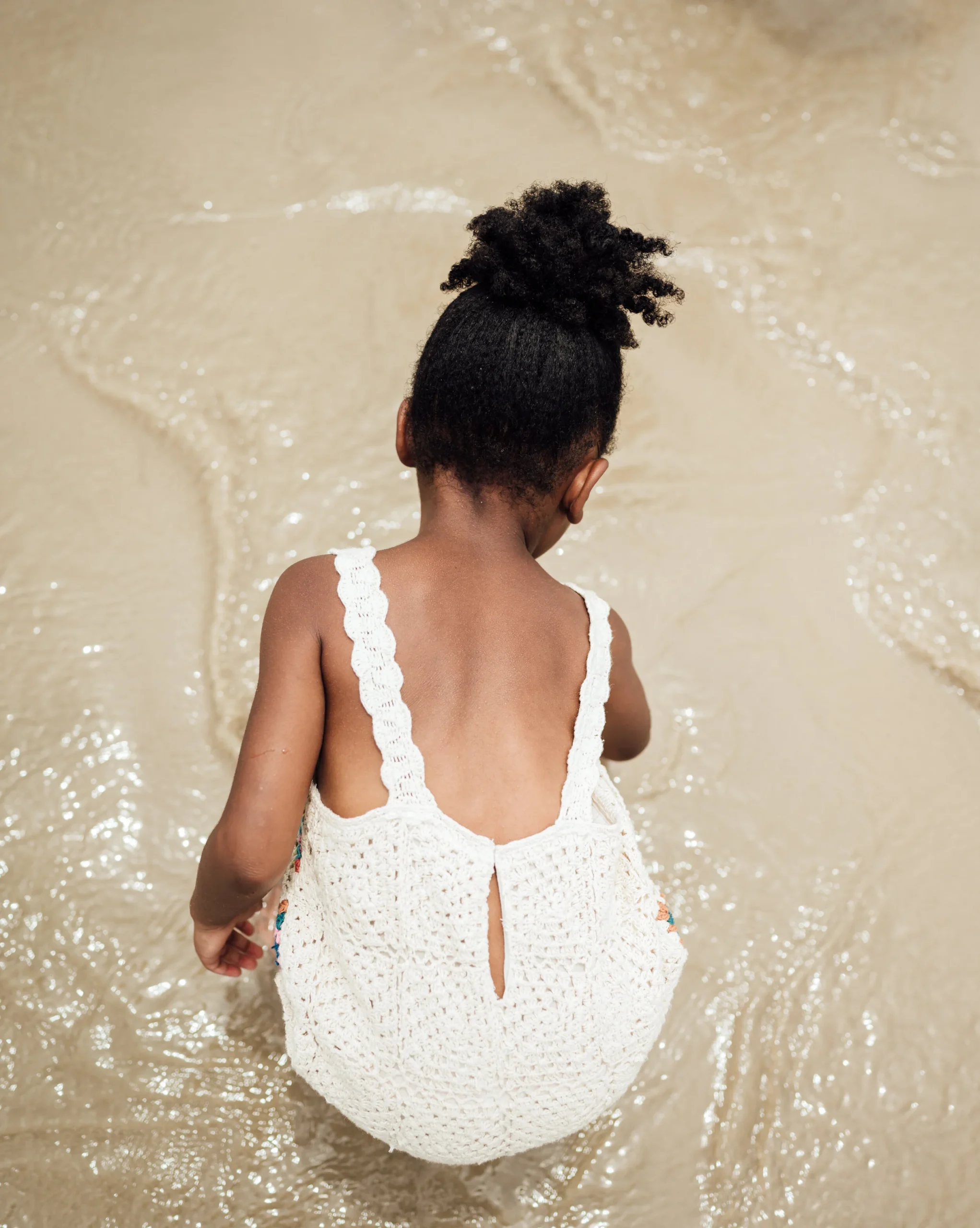 lili,+facing+away+from+camera,+playing+with+water+at+the+beach
