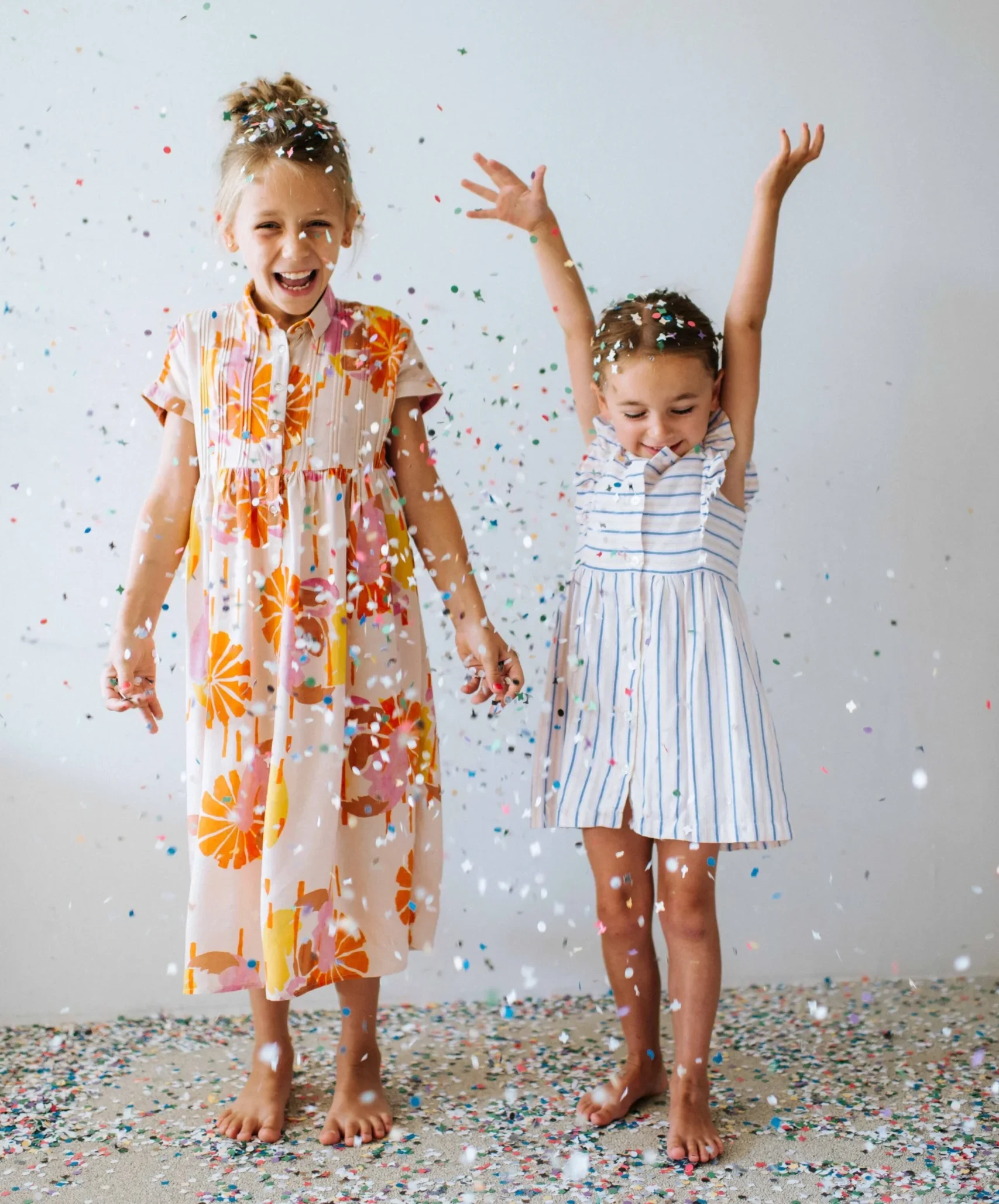 two+young+happy+girls+in+summer+dresses+playing+with+confetti